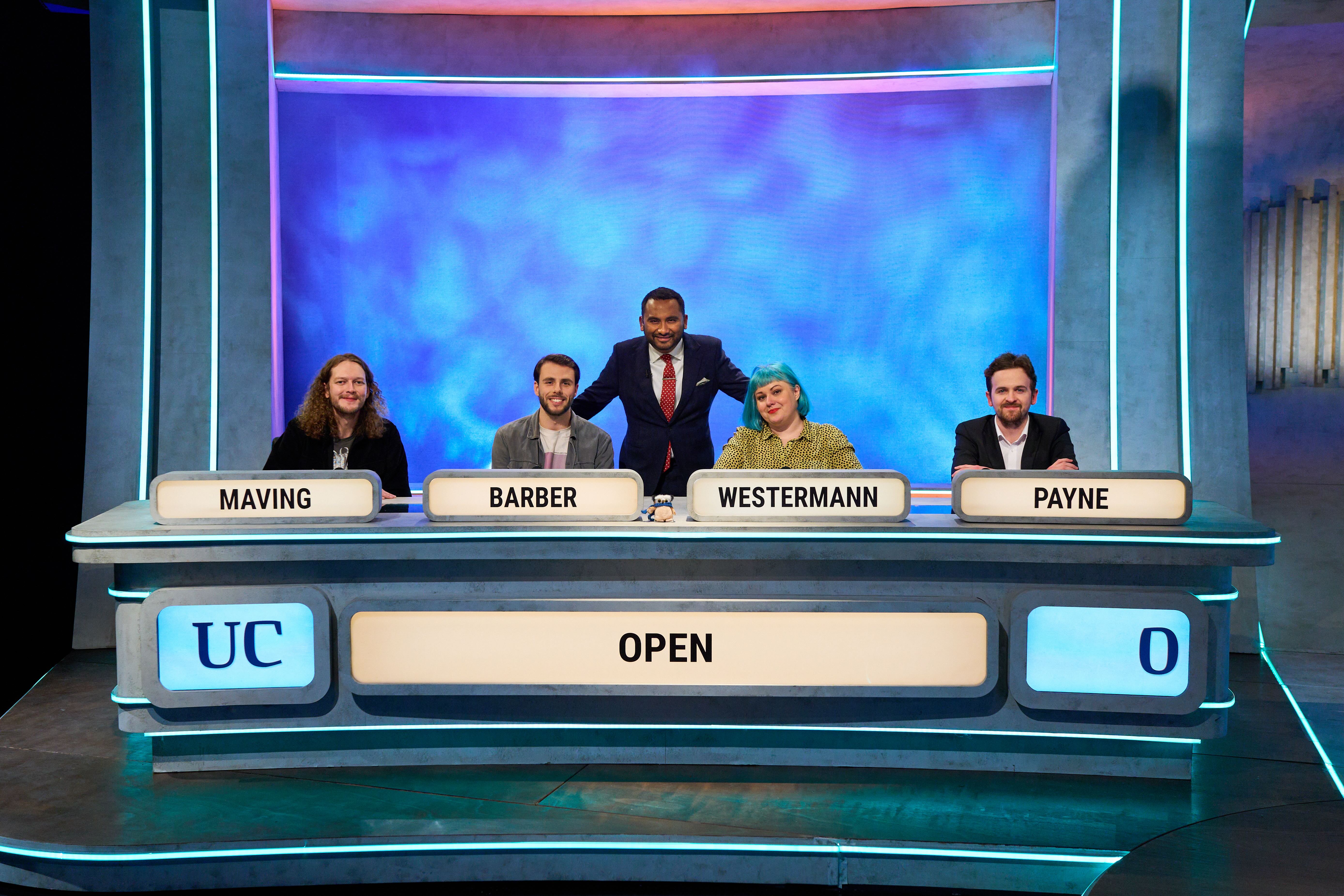 A photograph of the 2024 University Challenge team smiling at camera, from left to right Maving, Barber, Westermann, Payne, with presenter Amol Rajan in the centre.